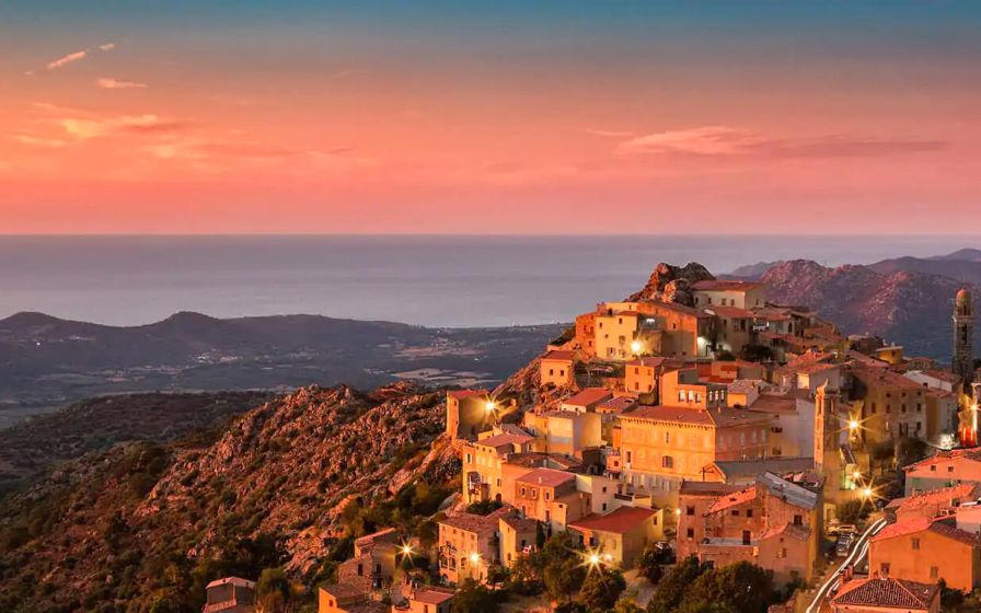 Il villaggio di Speloncato in Balagna, Corsica, baciato dal sole alla fine della serata, con lampioni e sentieri.