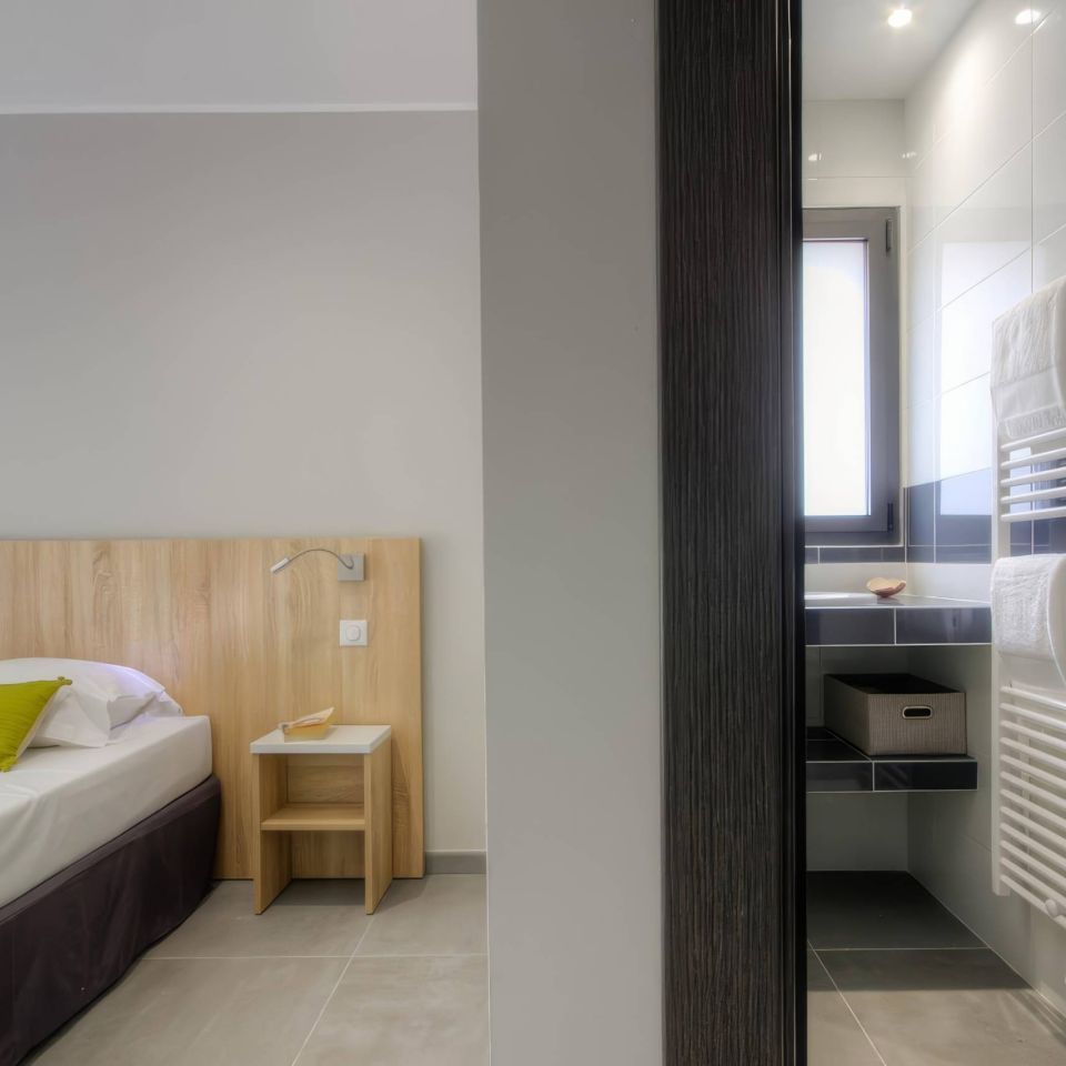 Modern room with wooden accents and an adjoining bathroom featuring white tiles and a towel rack.
