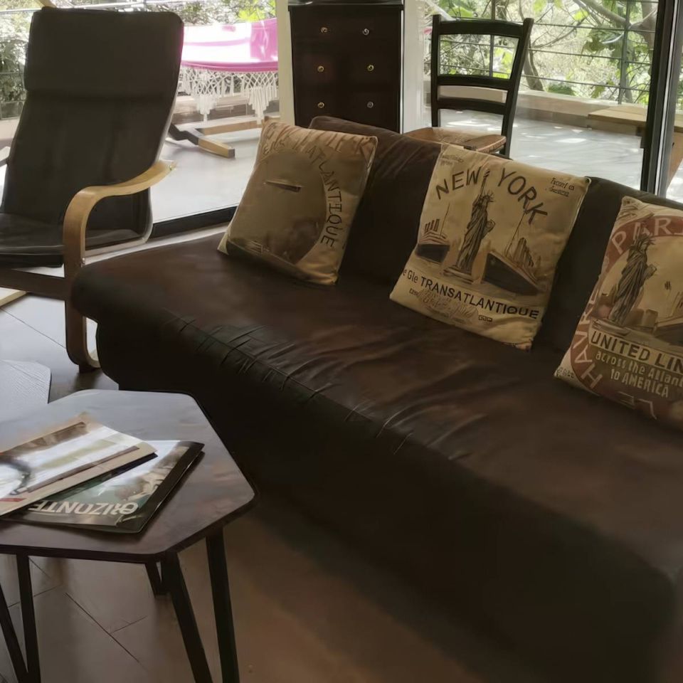 Un espace de vie confortable avec un canapé marron, des coussins décoratifs, une table d'appoint et une arrangement floral.