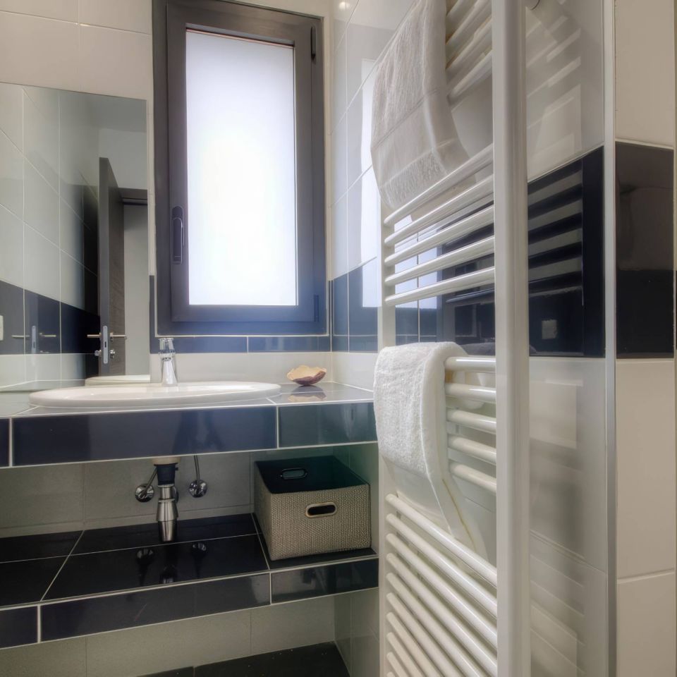 Modern bathroom featuring a sink, mirror, towel warmer, and window with a sleek, minimalist design.