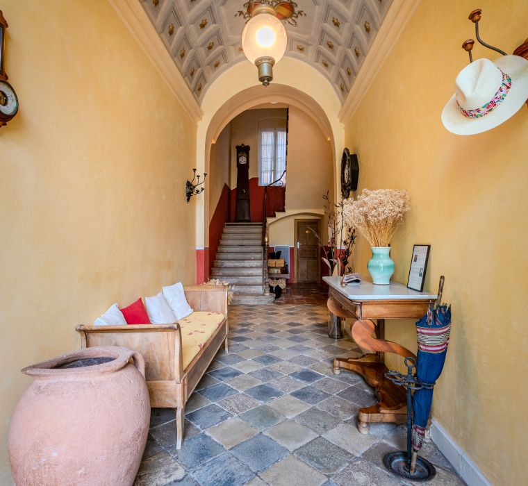 Un corridoio accogliente presenta una scala, un pavimento decorato, una panchina, decorazioni e luce naturale. Un'atmosfera calda e accogliente.