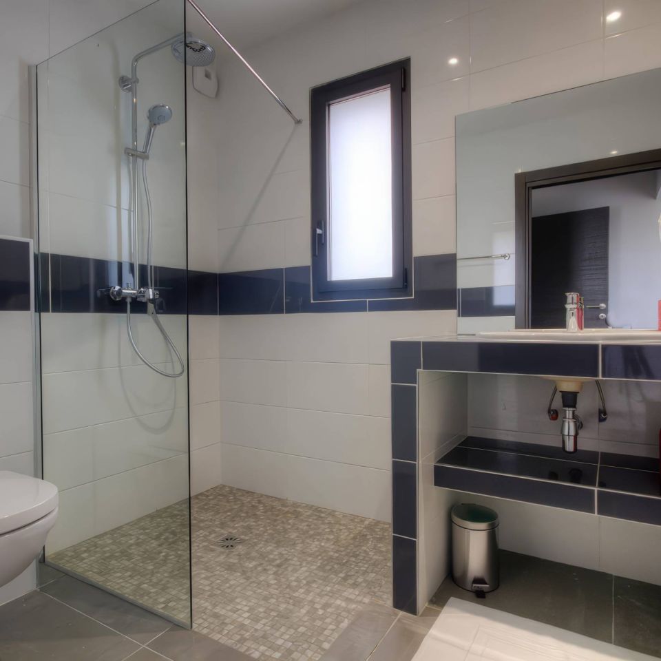 A modern bathroom featuring a glass shower, sleek toilet, and stylish sink with decorative baskets.