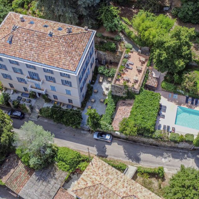 Vista aerea di una casa elegante con una piscina circondata da verde e aree residenziali. Soffusa di luce solare e accogliente.